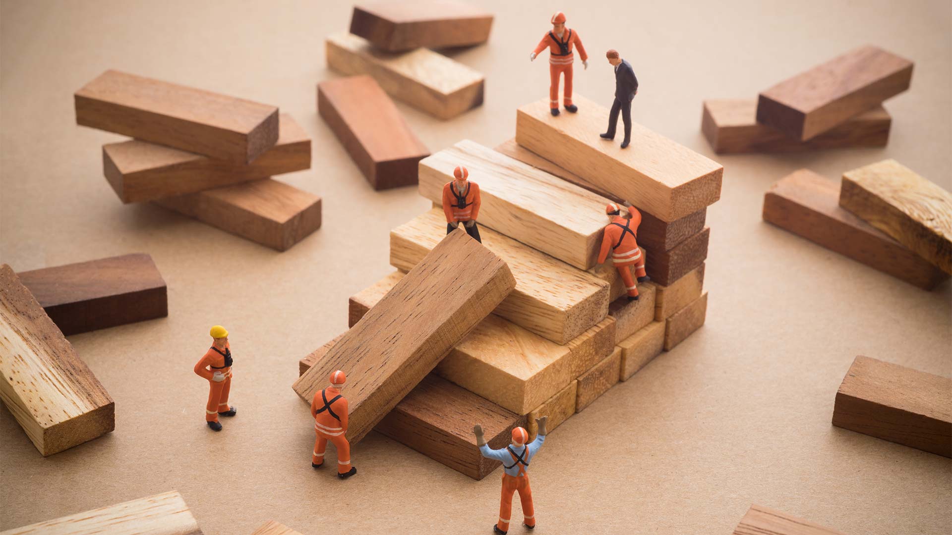 Small people figurines building steps out of wooden jenga pieces