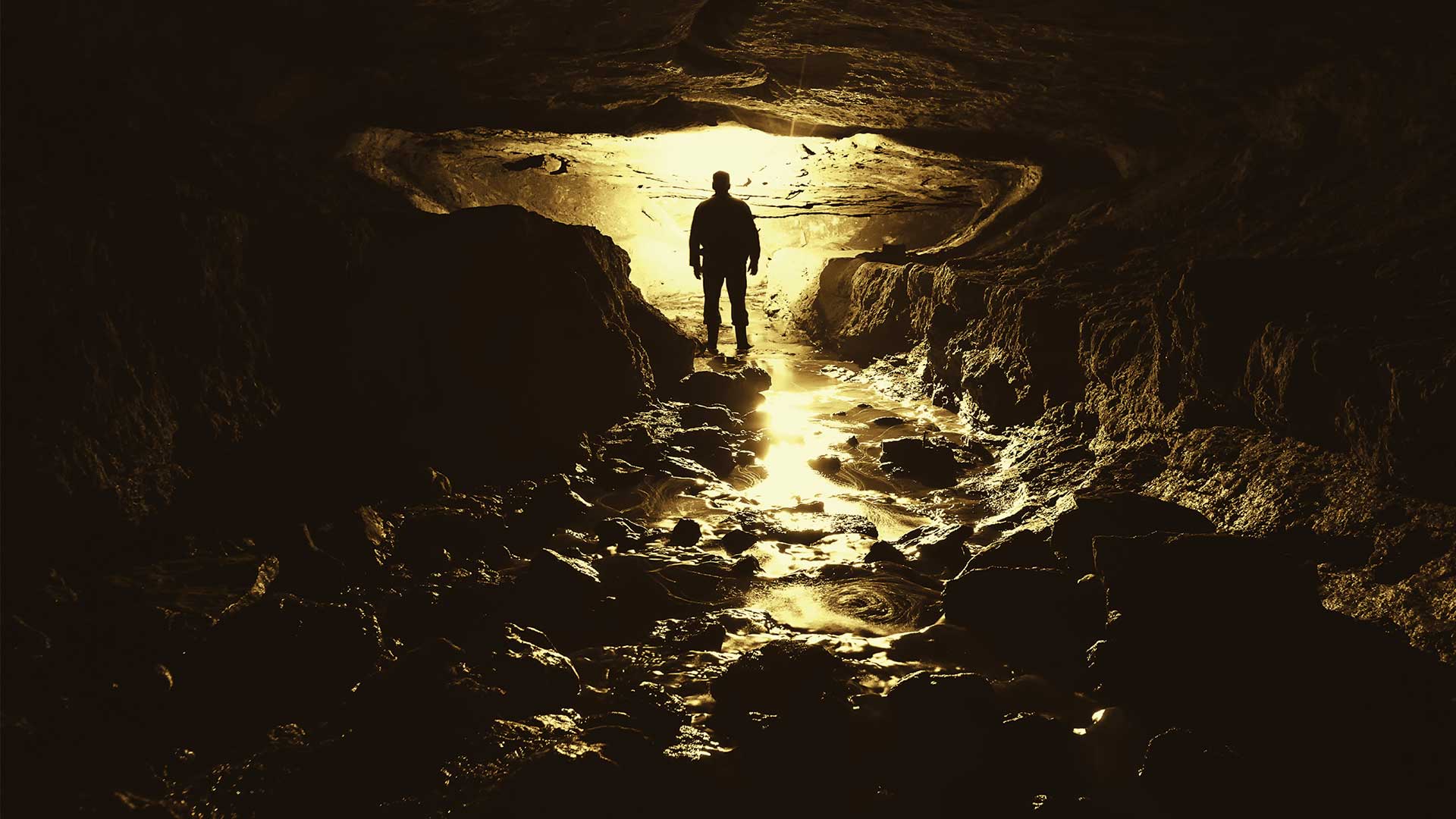 Silhouette of person in a dark cave with only a small bit of light
