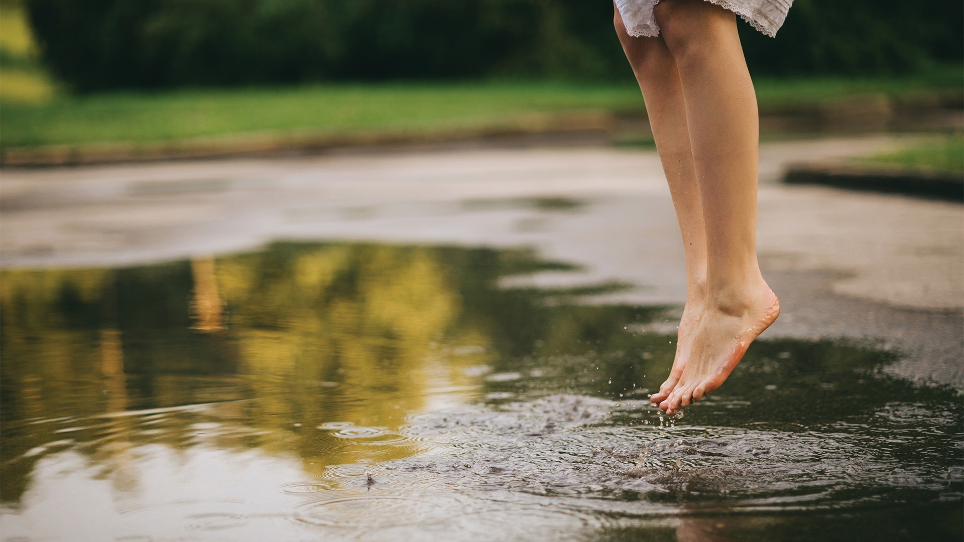 Woman jumping barefoot over a puddle