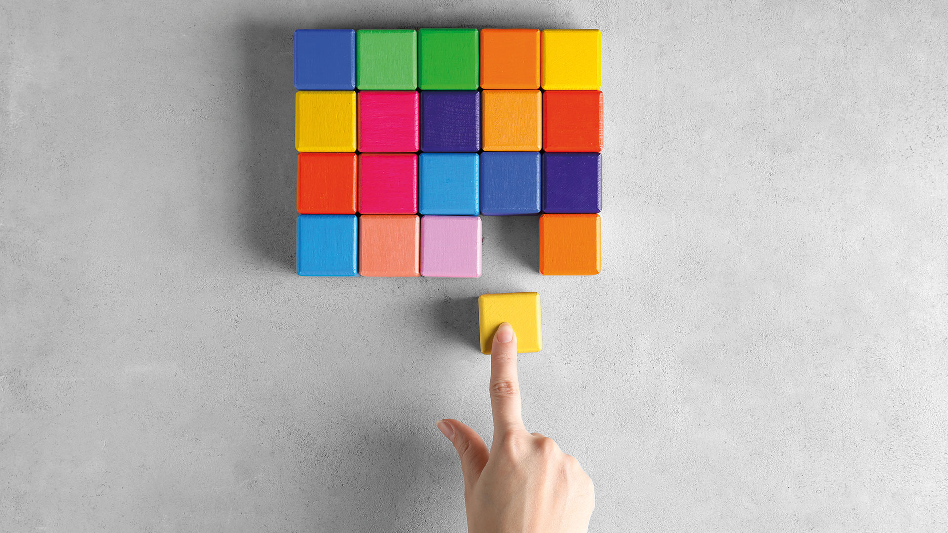 Person moving colour block into a bunch of other colour blocks