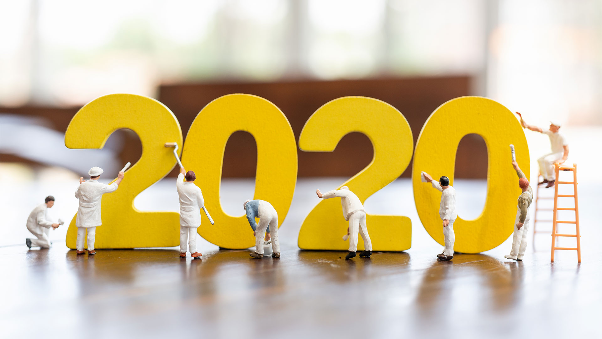 Miniature figurines of workers painting the number 2020