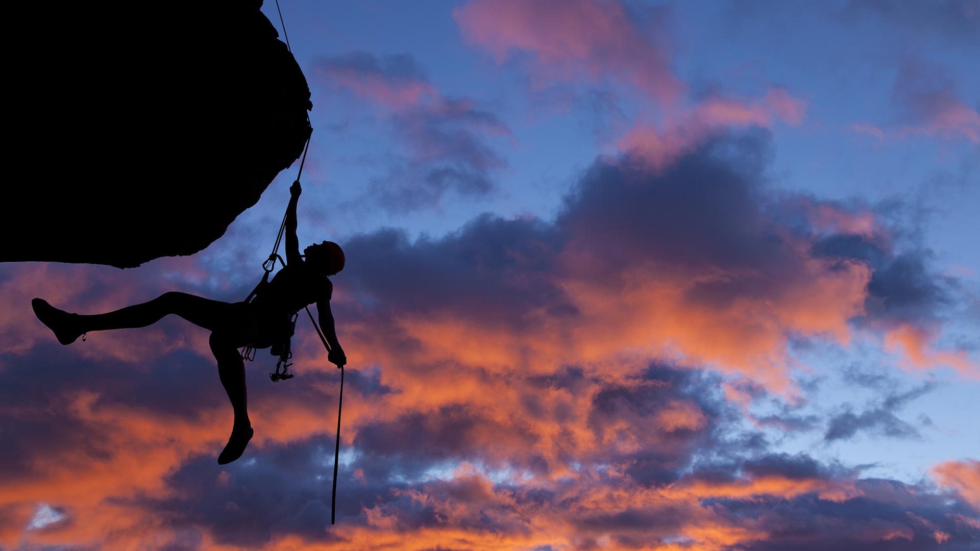Person rock climbing during sunset
