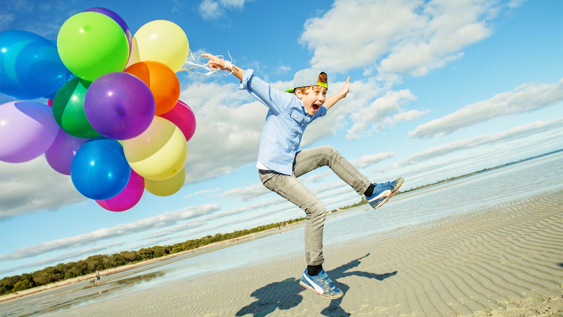 Boy with a load of balloons lifting off of the floor
