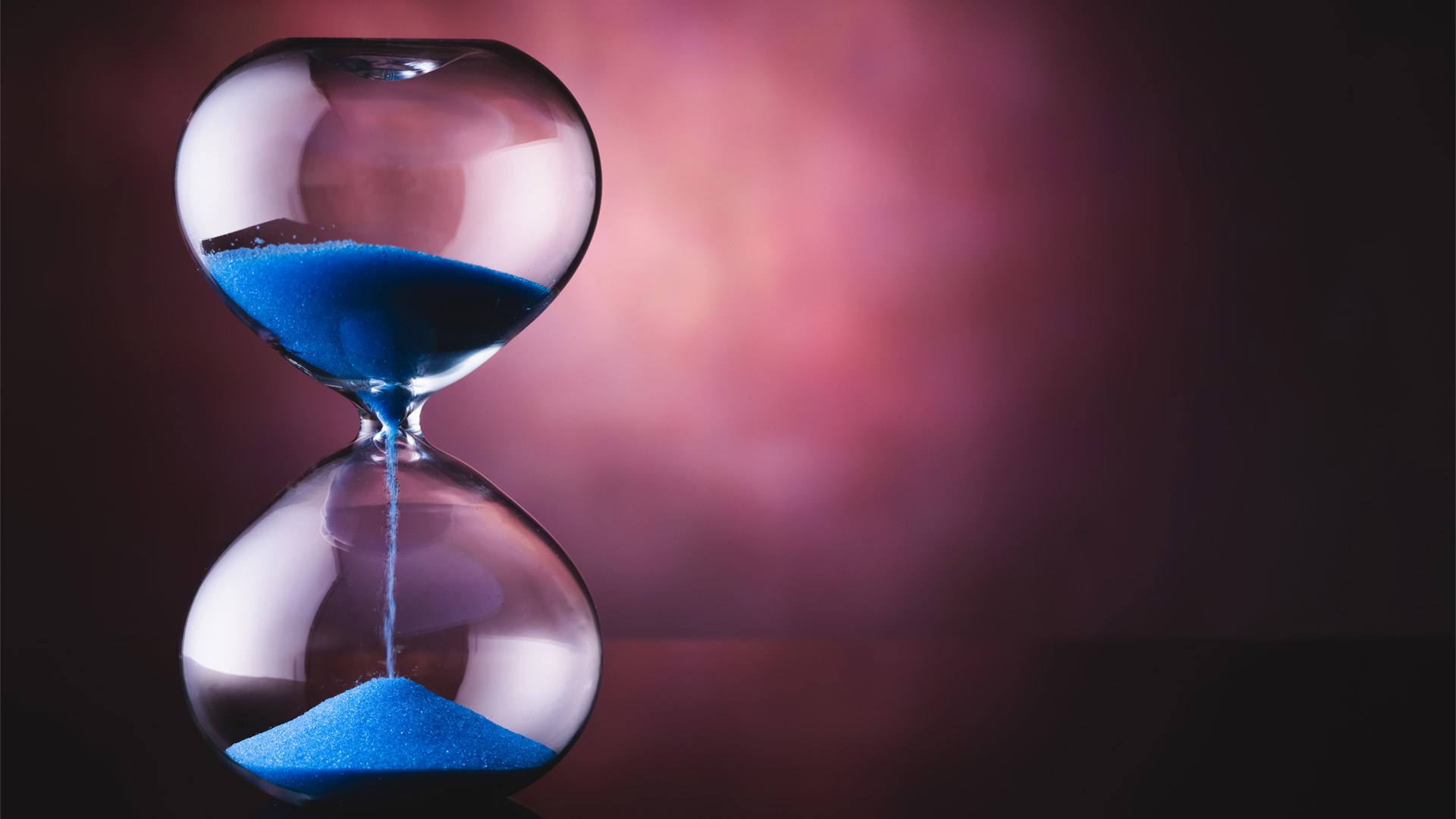 A glass timer with blue sand