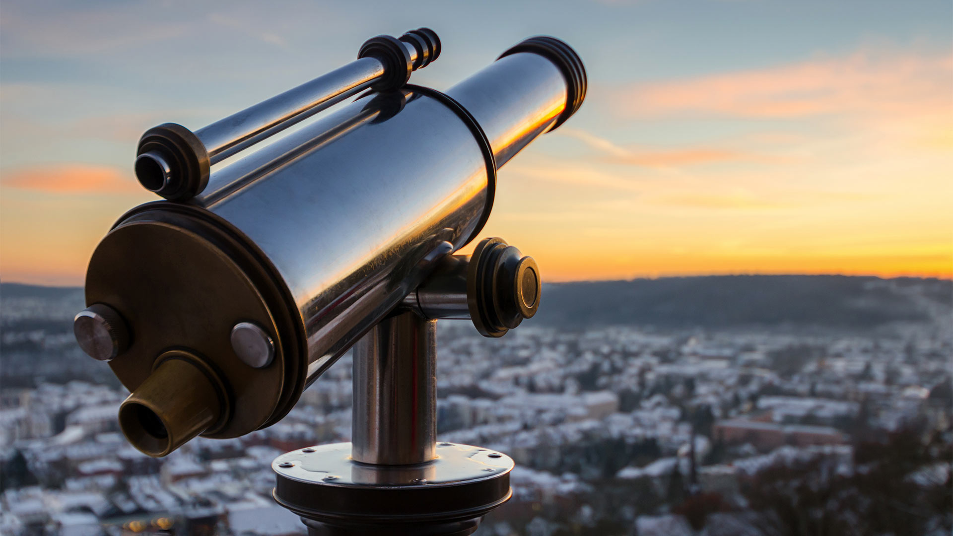 A monocular telescope looking over a town during sunset