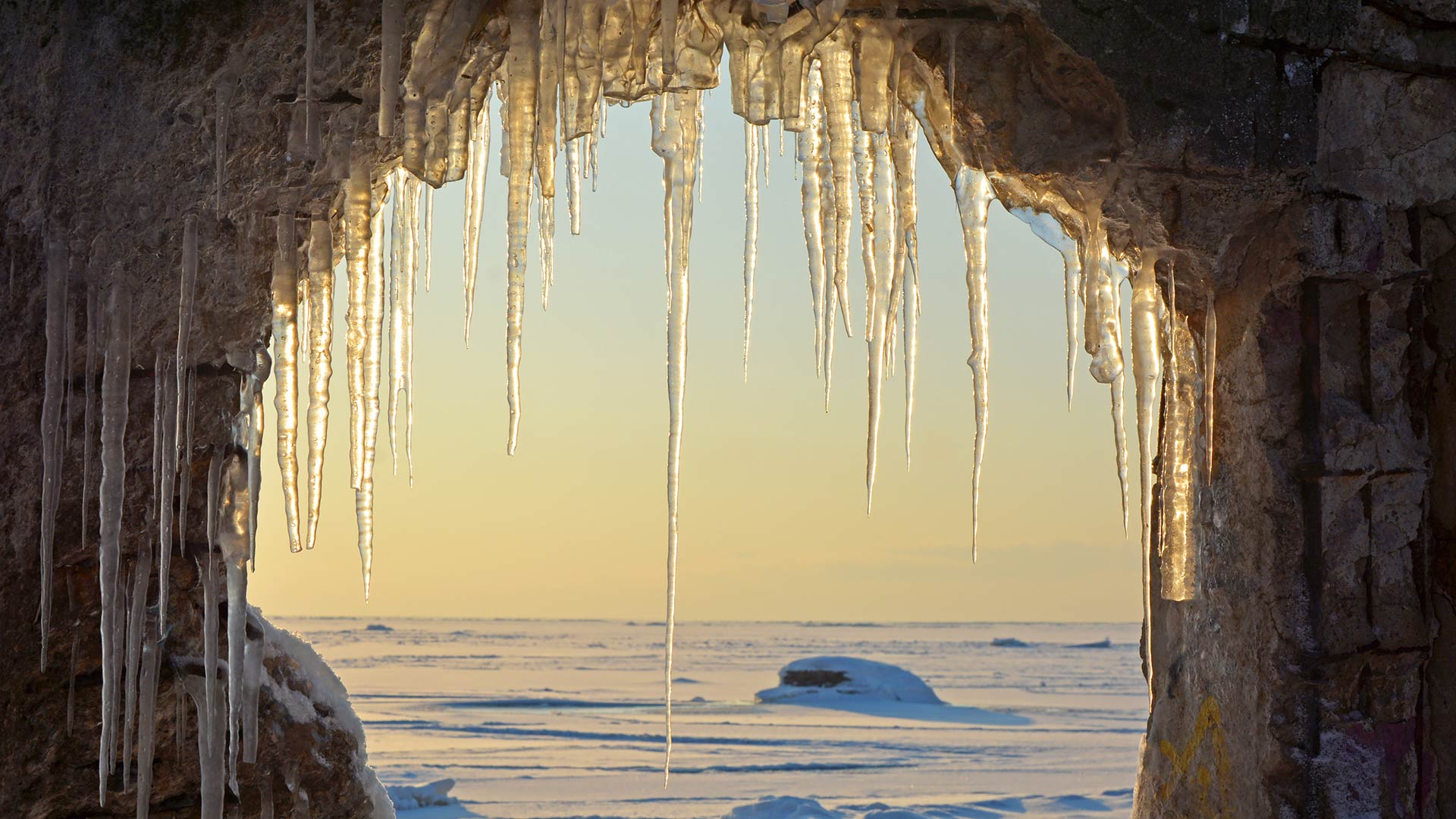 Frozen sea viewed through arch of icicles