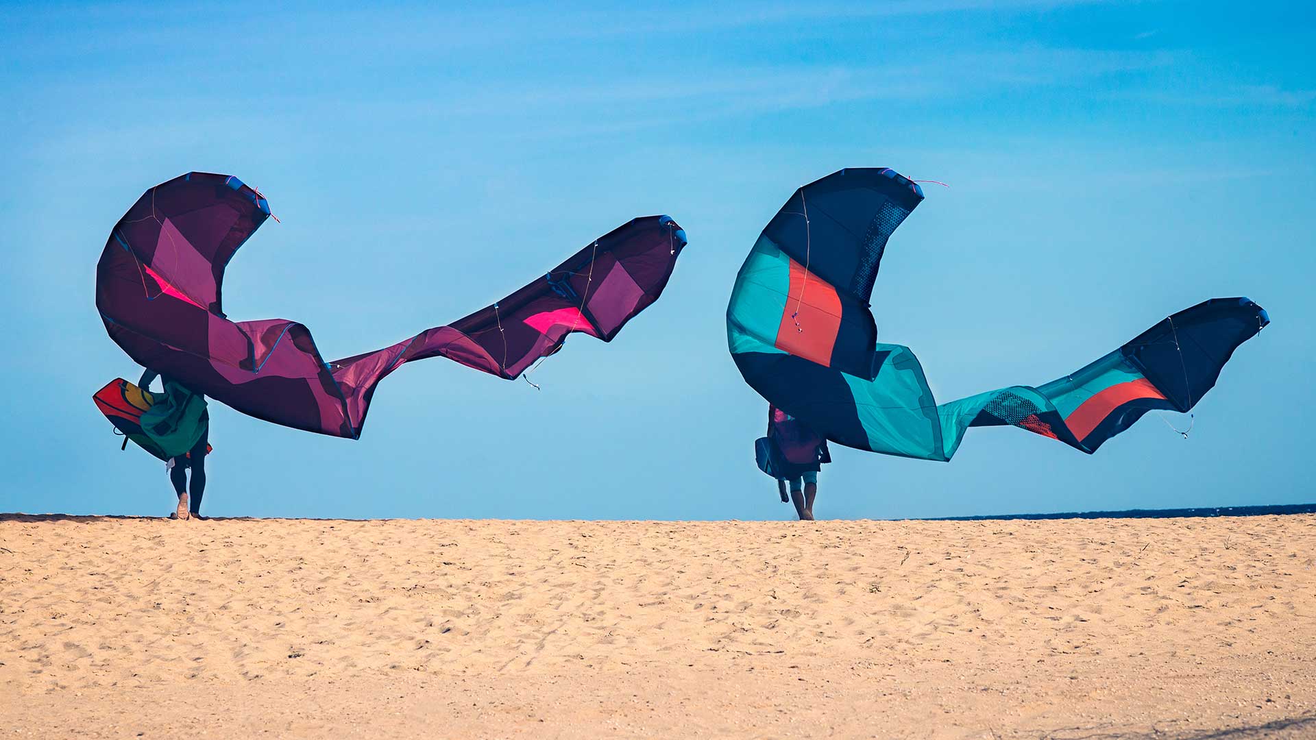 Two friends on a beach with big butterfly wing kites