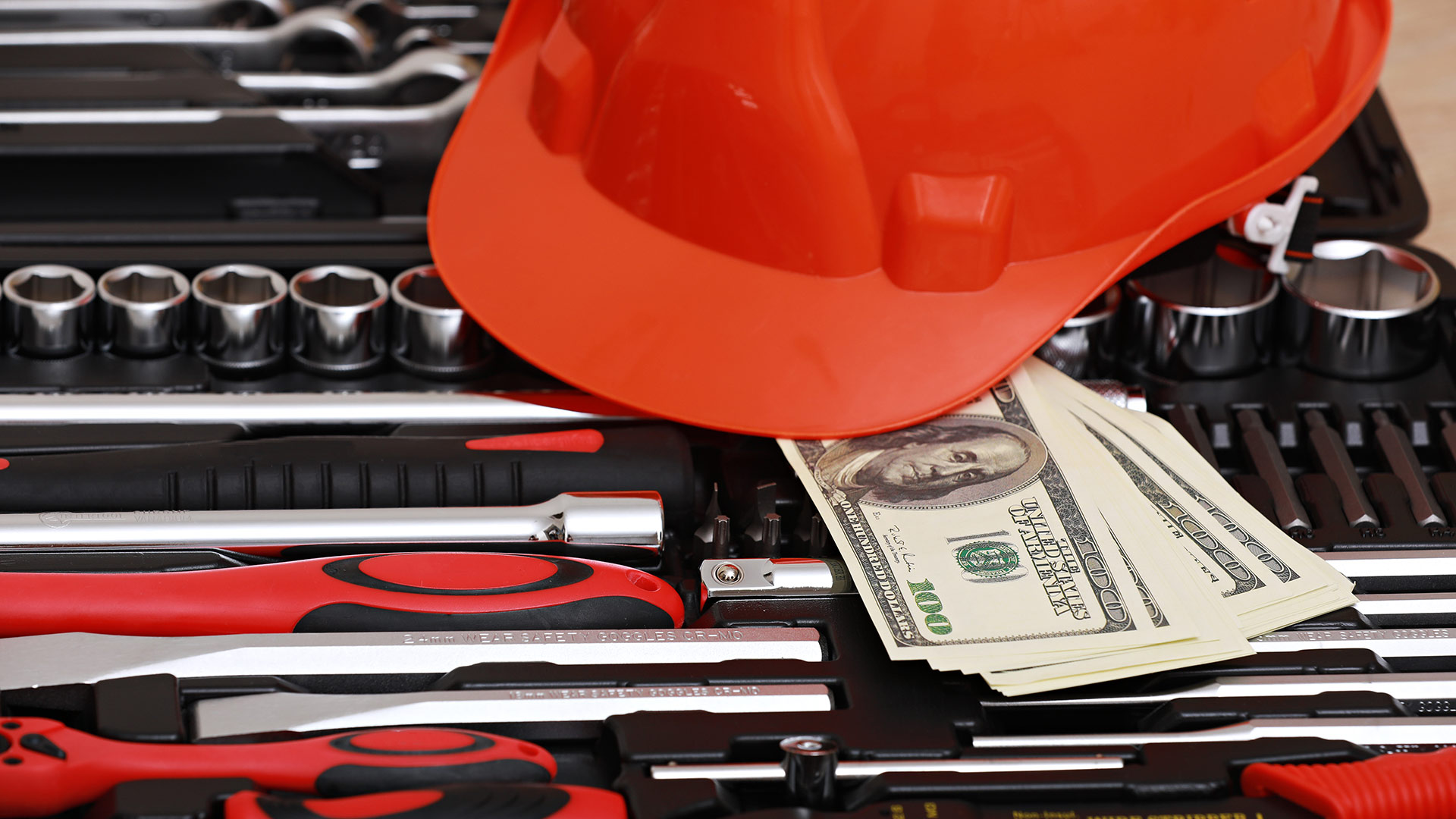 Builders hat and tools with a bunch of dollars