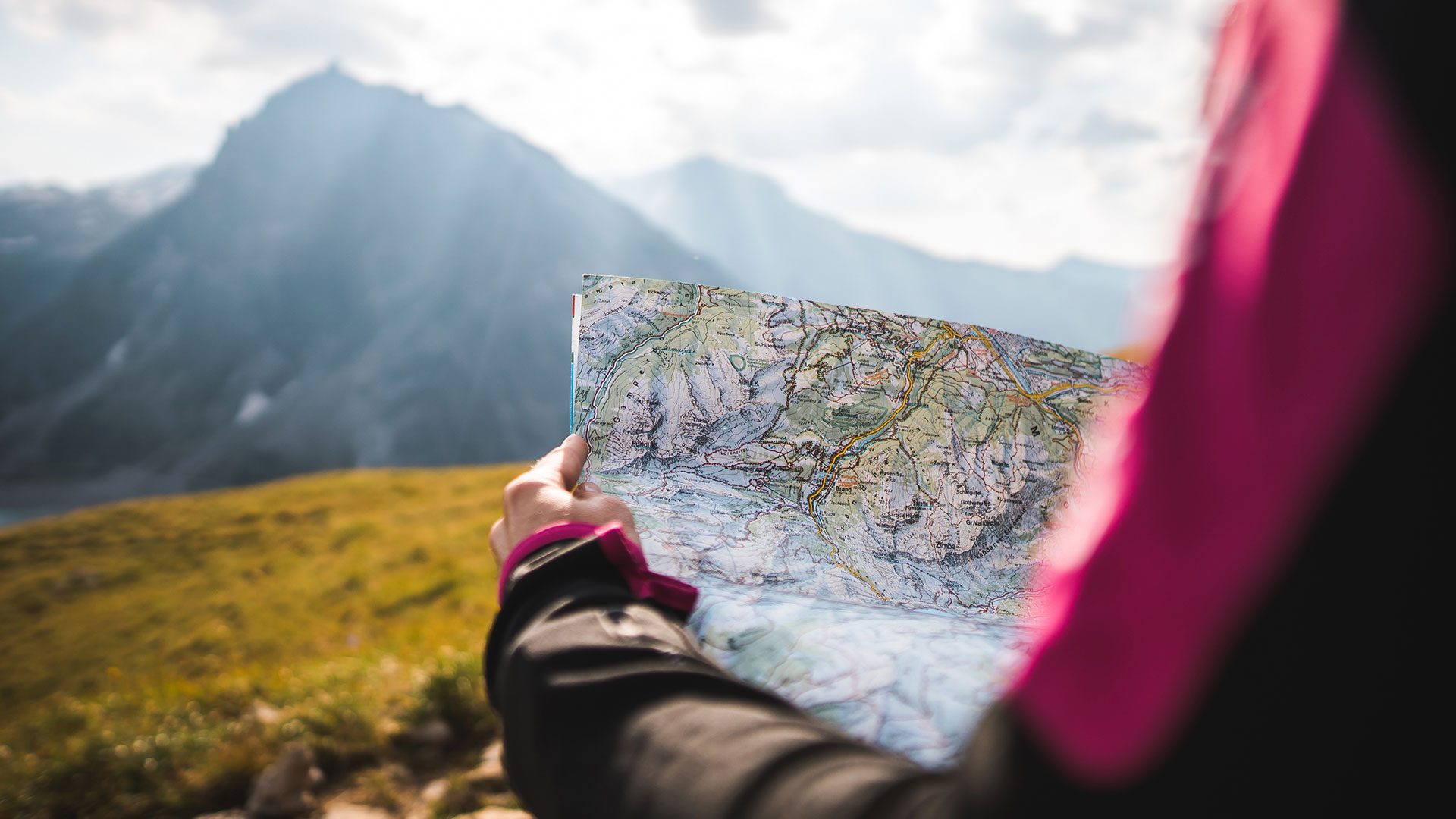 Adventurous person navigating mountains using a map