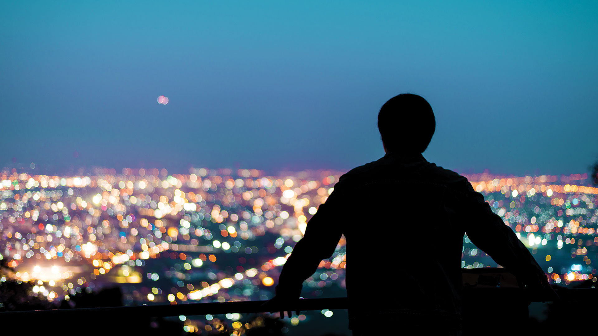 Silhouette of man looking above city at night