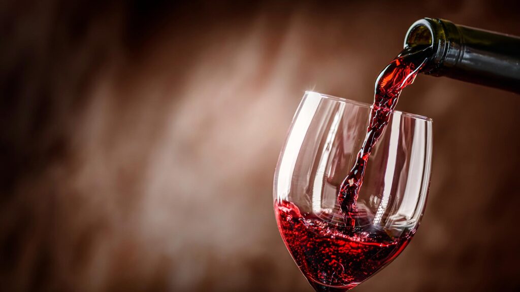 Bottle of red wine being poured into a wine glass