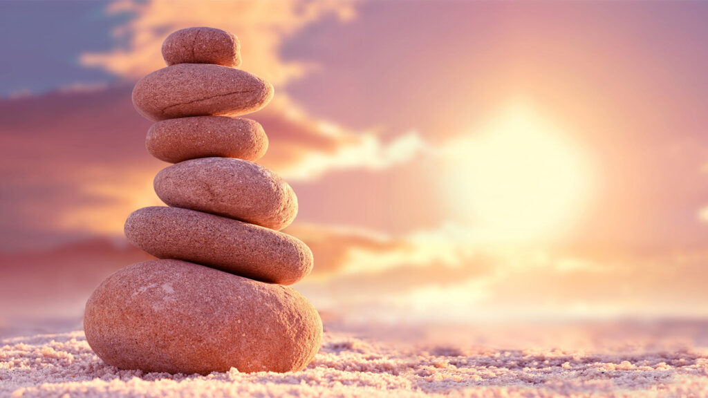 Stones stacked into a tower on the beach at sunset