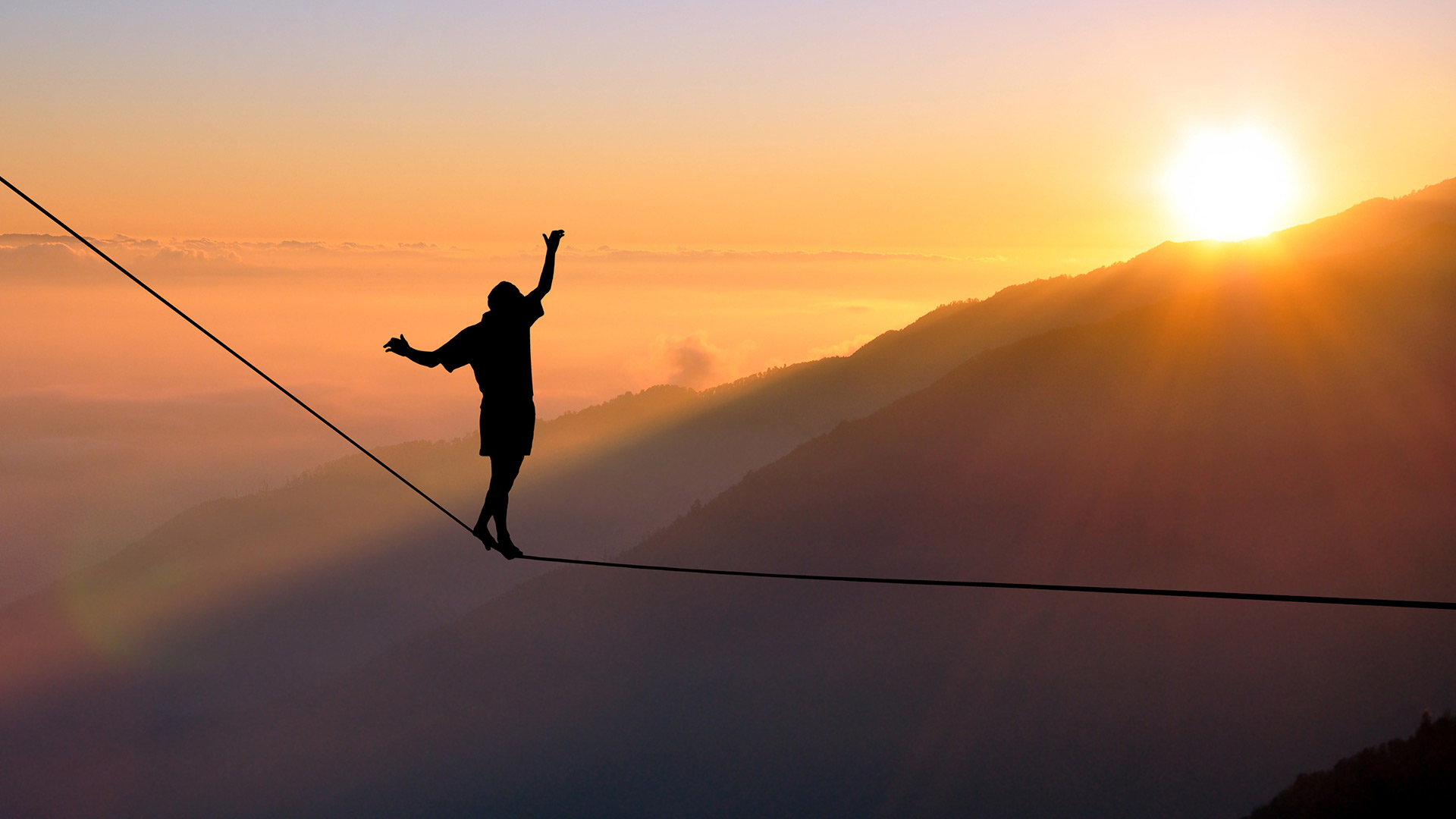 Person balancing on a slackline during sunset