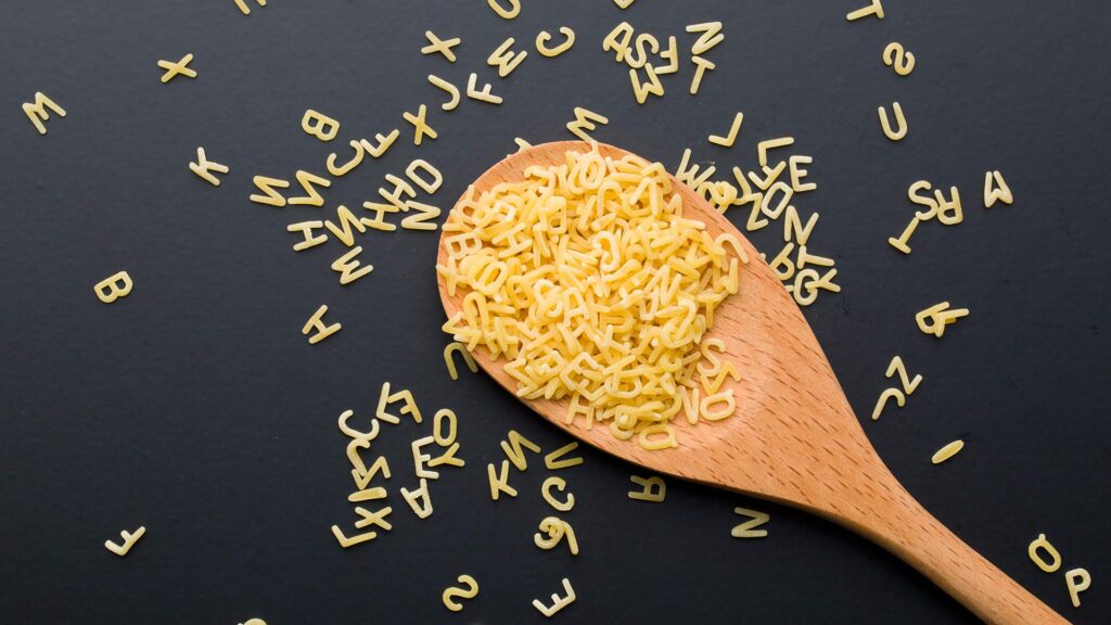 Alphabet pasta on and surrounding a wooden spoon