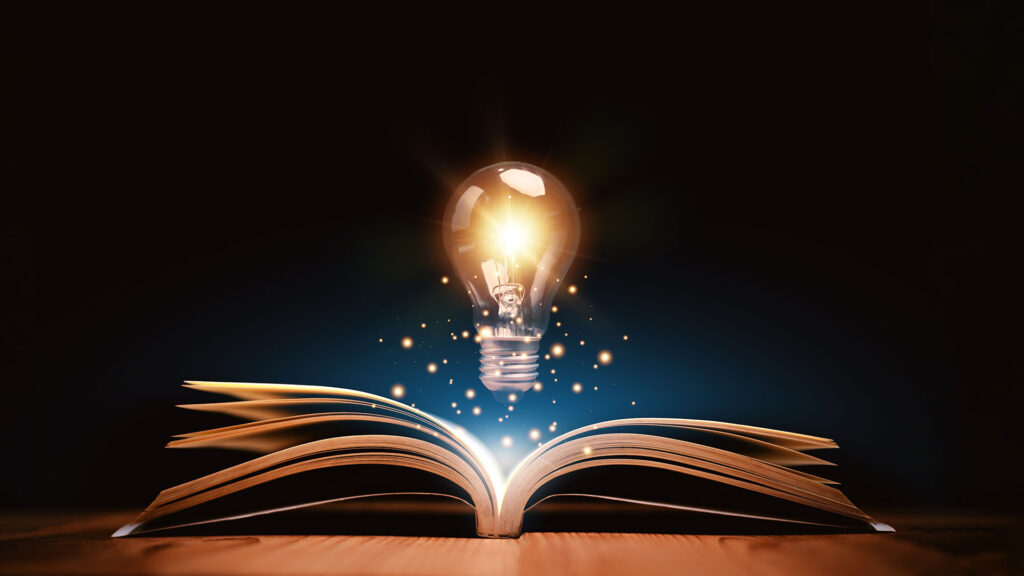 Lit up light bulb hovering over a book