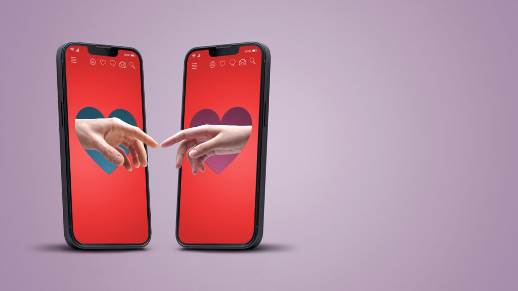 Two mobile phones symbolising dating apps with two peoples hands reaching each others