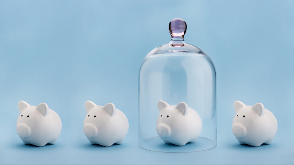 Piggy banks with one trapped under a glass jar