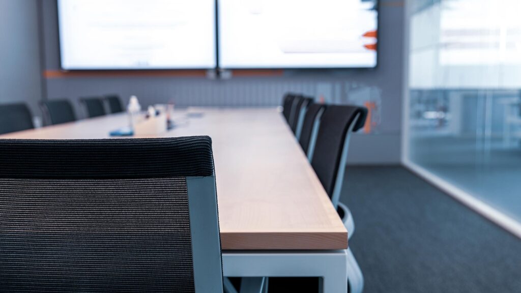 Empty board room with table and chairs and working screen