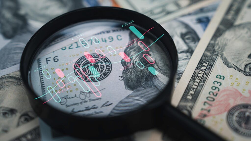 Magnifying glass on top of dollar notes, showing stock chart