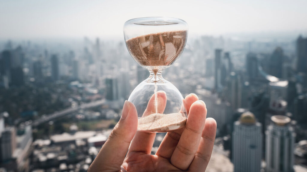 Person holding hourglass with cityscape in the background