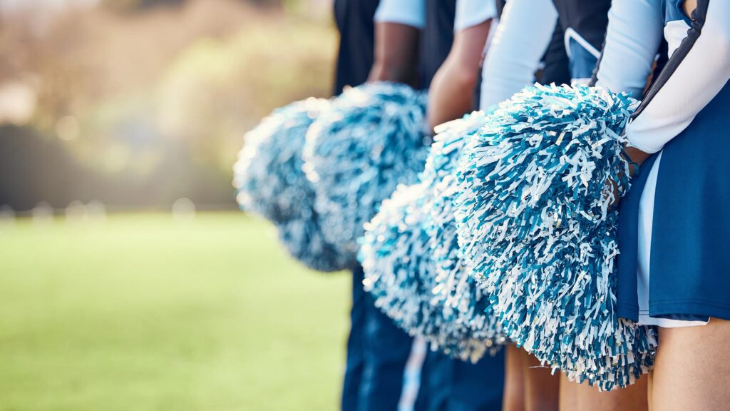 Cheerleaders standing in line with their pom poms