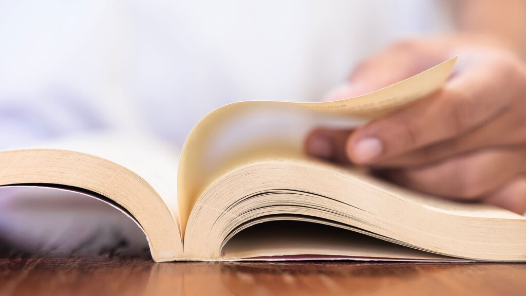 Close up of person reading book and turning the page