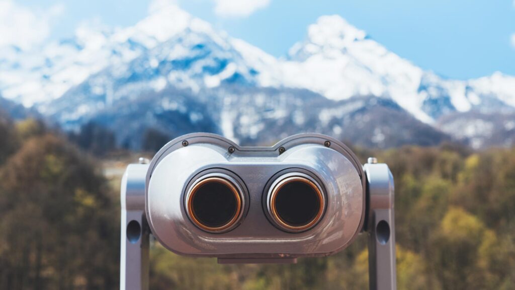 Tourists telescope looking out a snowy mountains