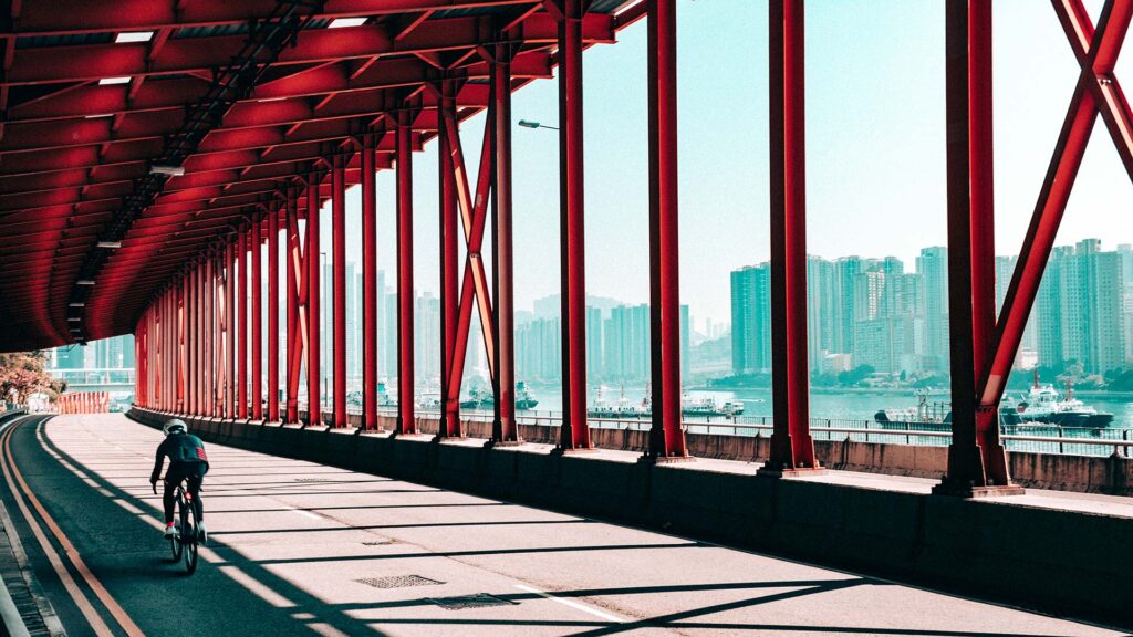 Cyclist under a red bridge