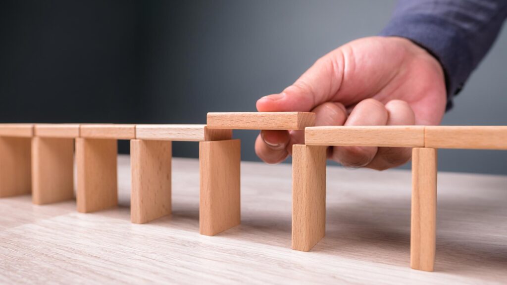 Person holding wooden blocks to build a bridge