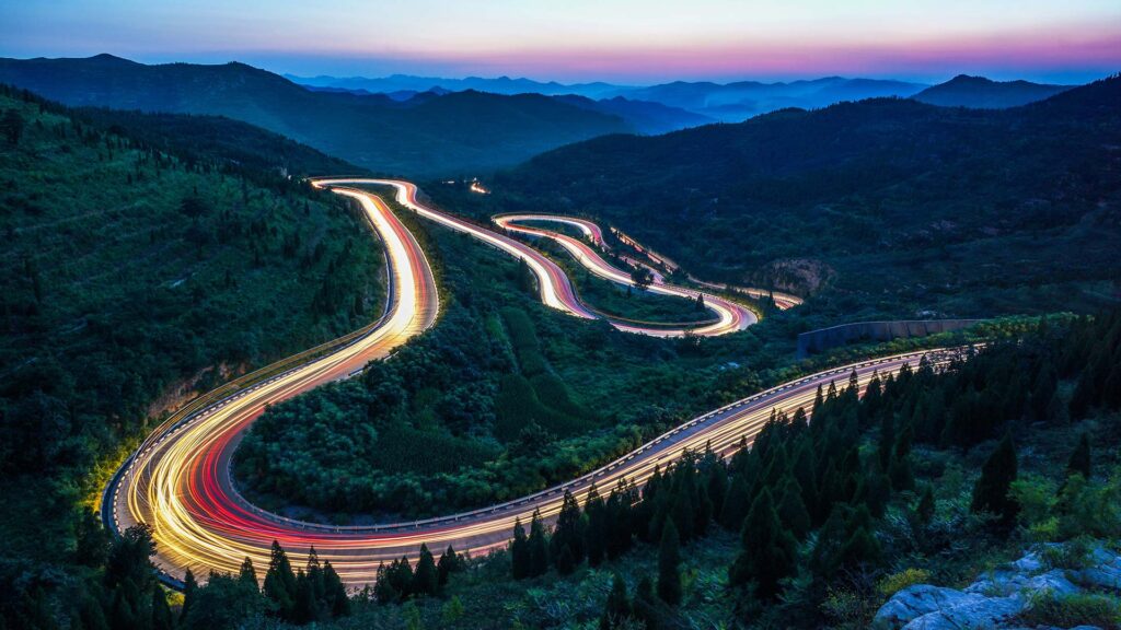 Winding road in the mountains with car light trails