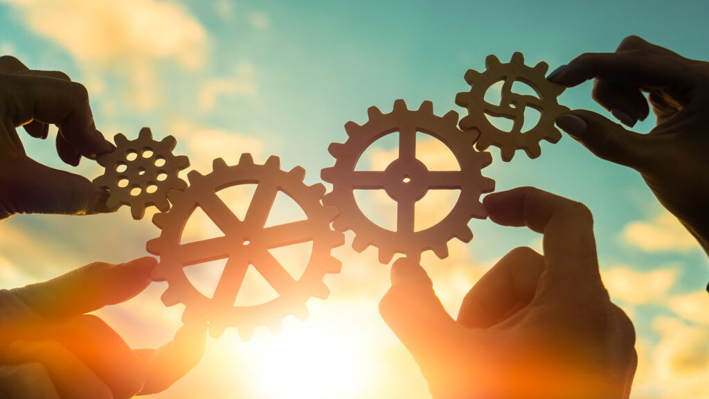 Group of people working together to make the cogs fit together