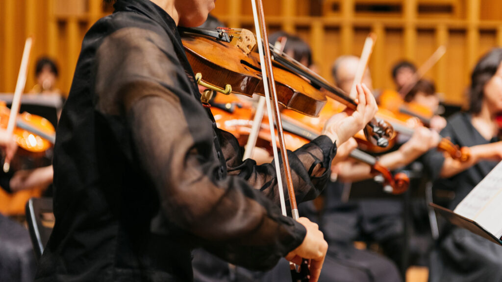Close up of person playing violin in orchestra