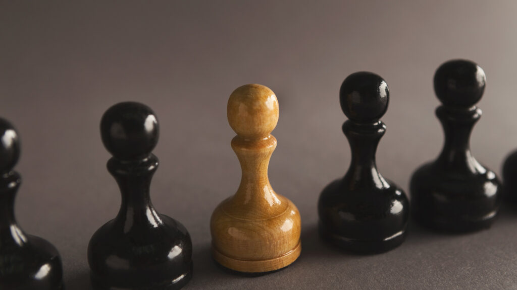 Wooden chess pawn in a line of black pawns.