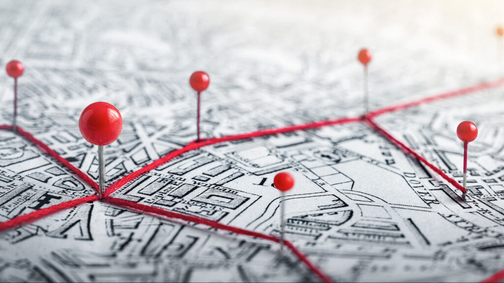 Photo of roadmap with red pins and lines.