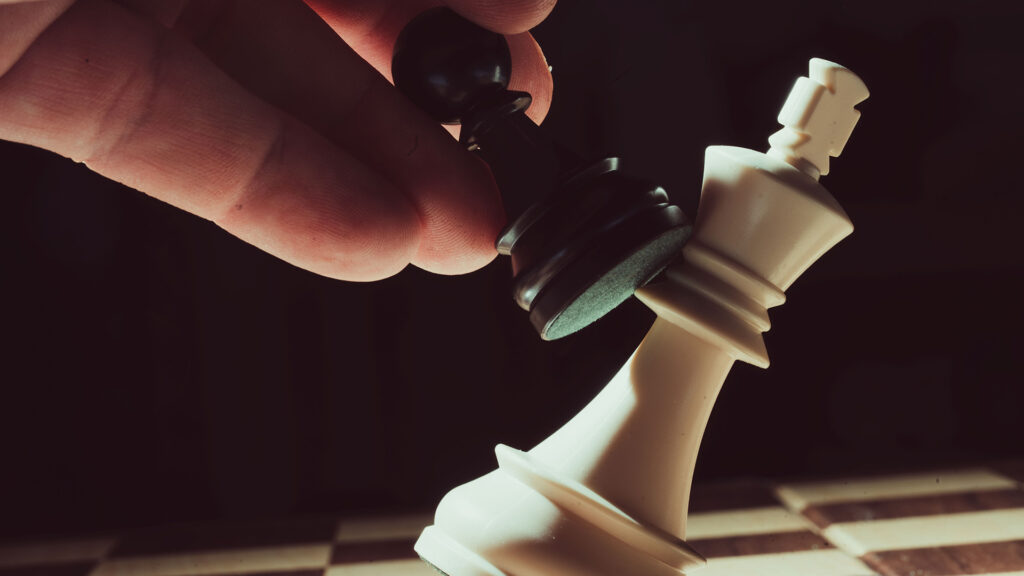 Photo of pawn chess piece attacking king piece.