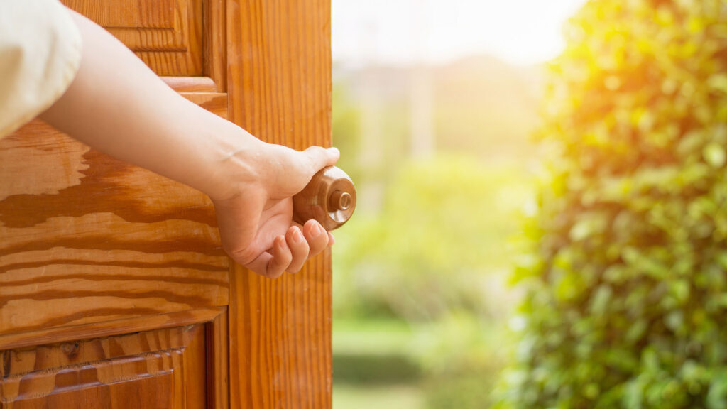 Person opening a door to reveal a beautiful garden
