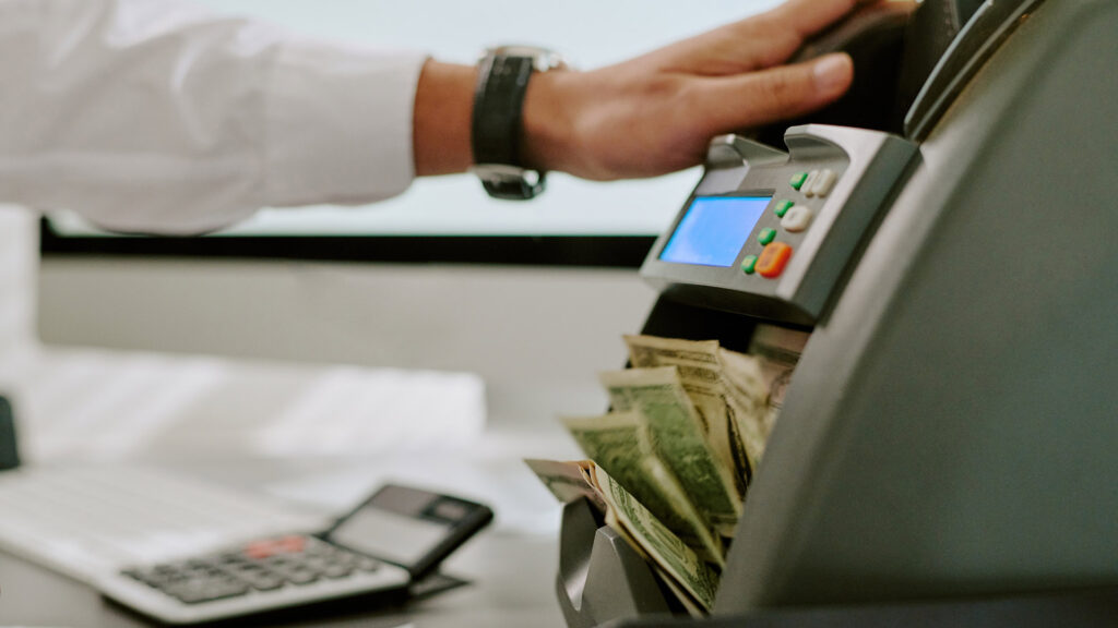 Person using banknote counting machine.