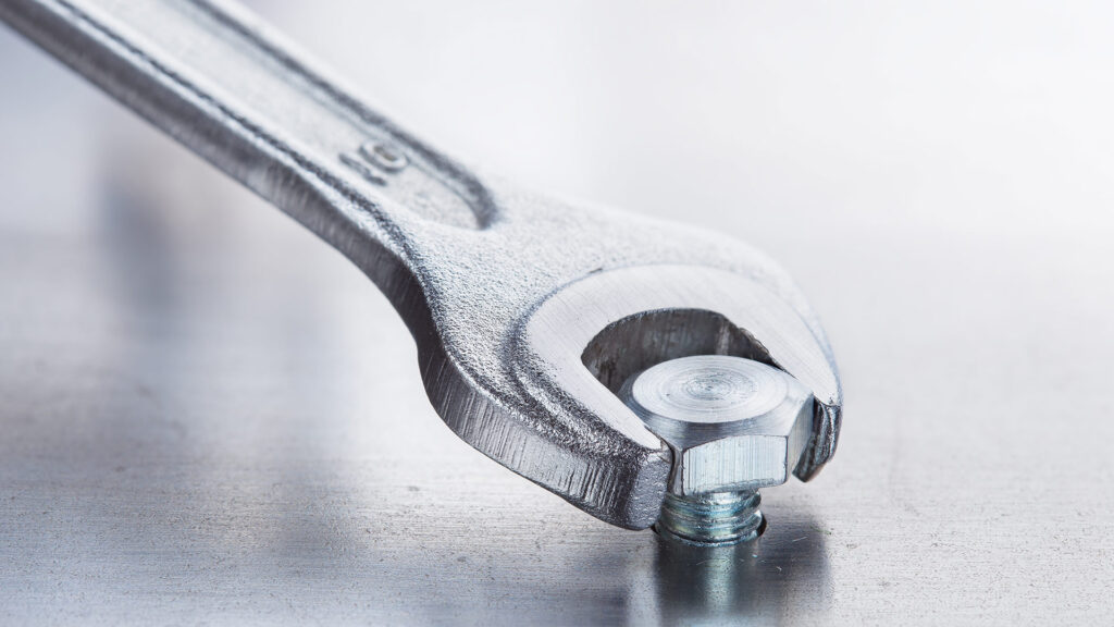 Shiny wrench screwing bolt.