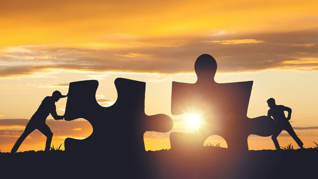 Silhouette of two people pushing the puzzle pieces together