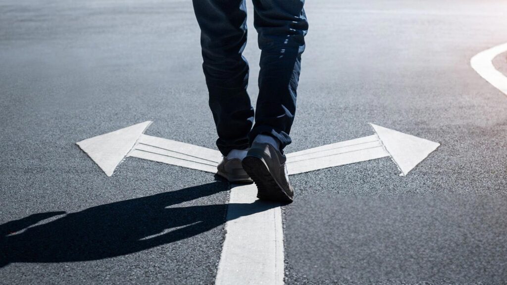 Person walking on a road with an arrow pointing in two directions