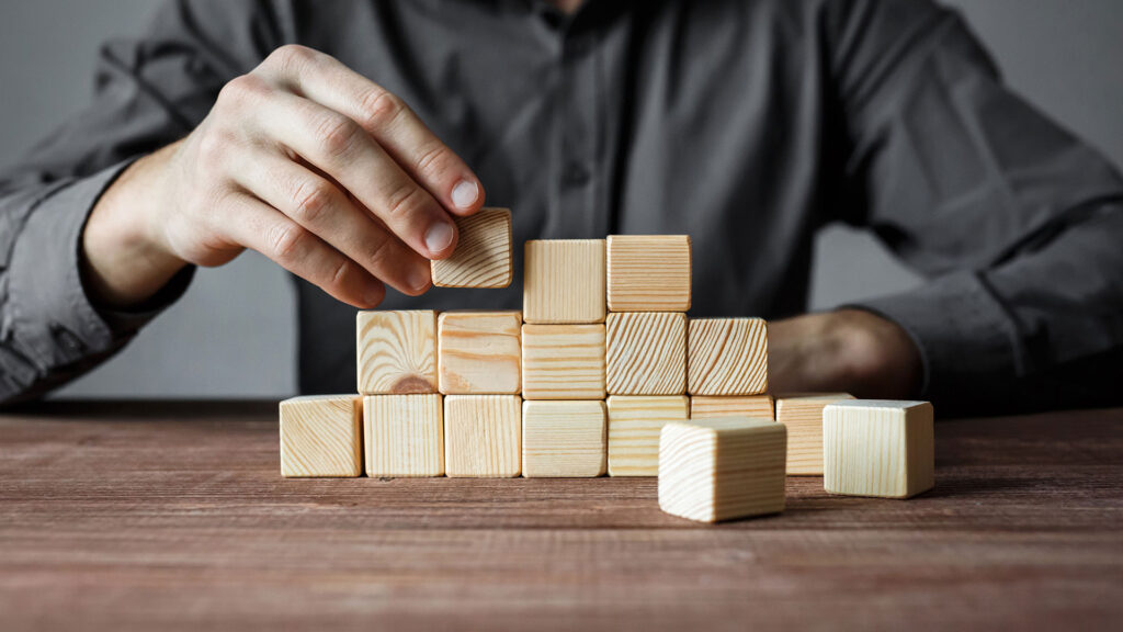 Person taking blocks off pyramid.