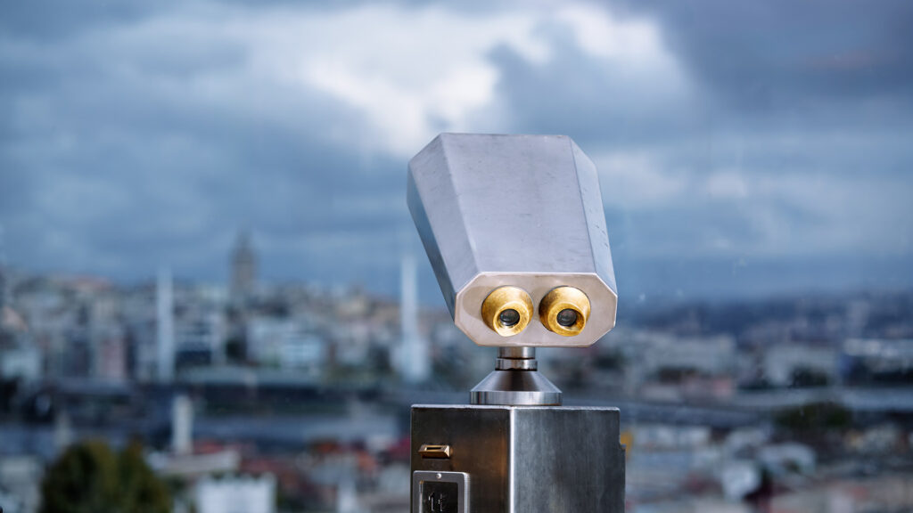 Viewing binoculars overlooking cloudy city.